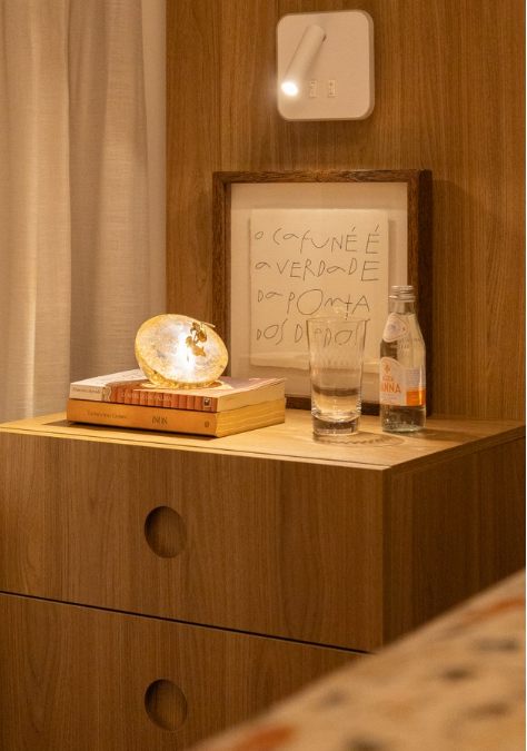 Criado-mudo com luminária de madrepérola, livros e quadro autoral